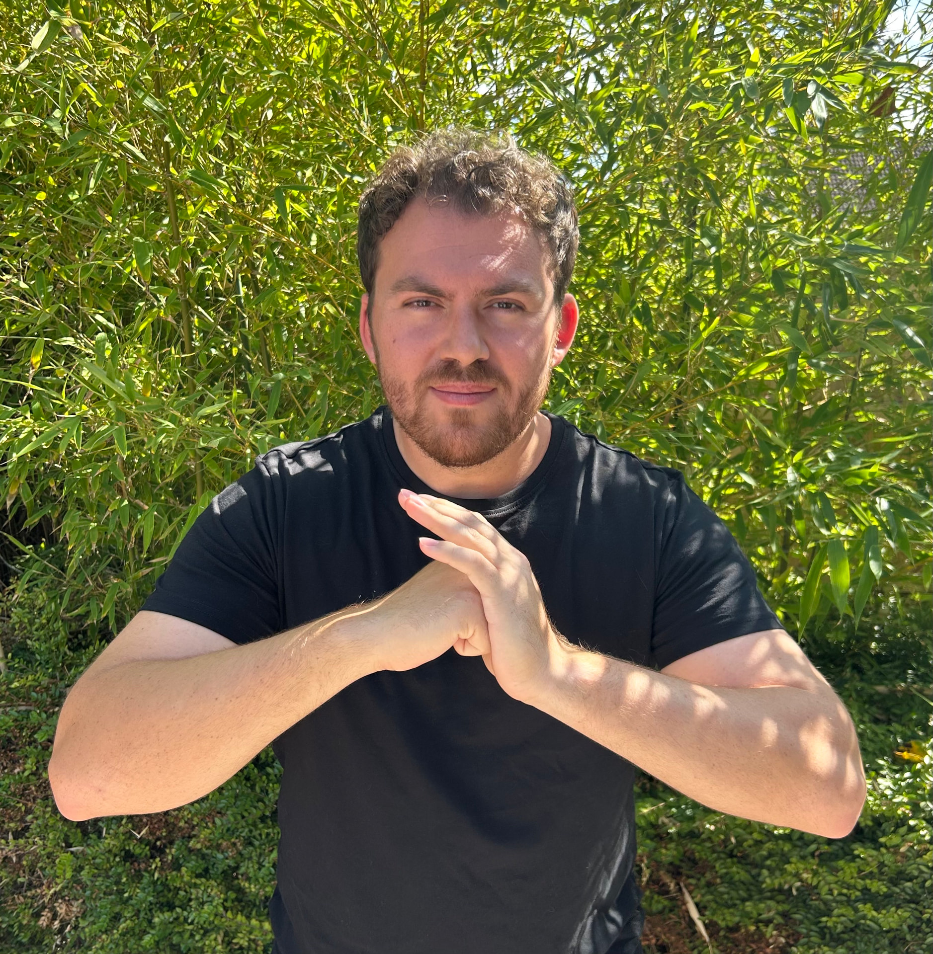 Archie Dunnett, founder of Bamboo Studios, performing a traditional martial arts salute in front of bamboo